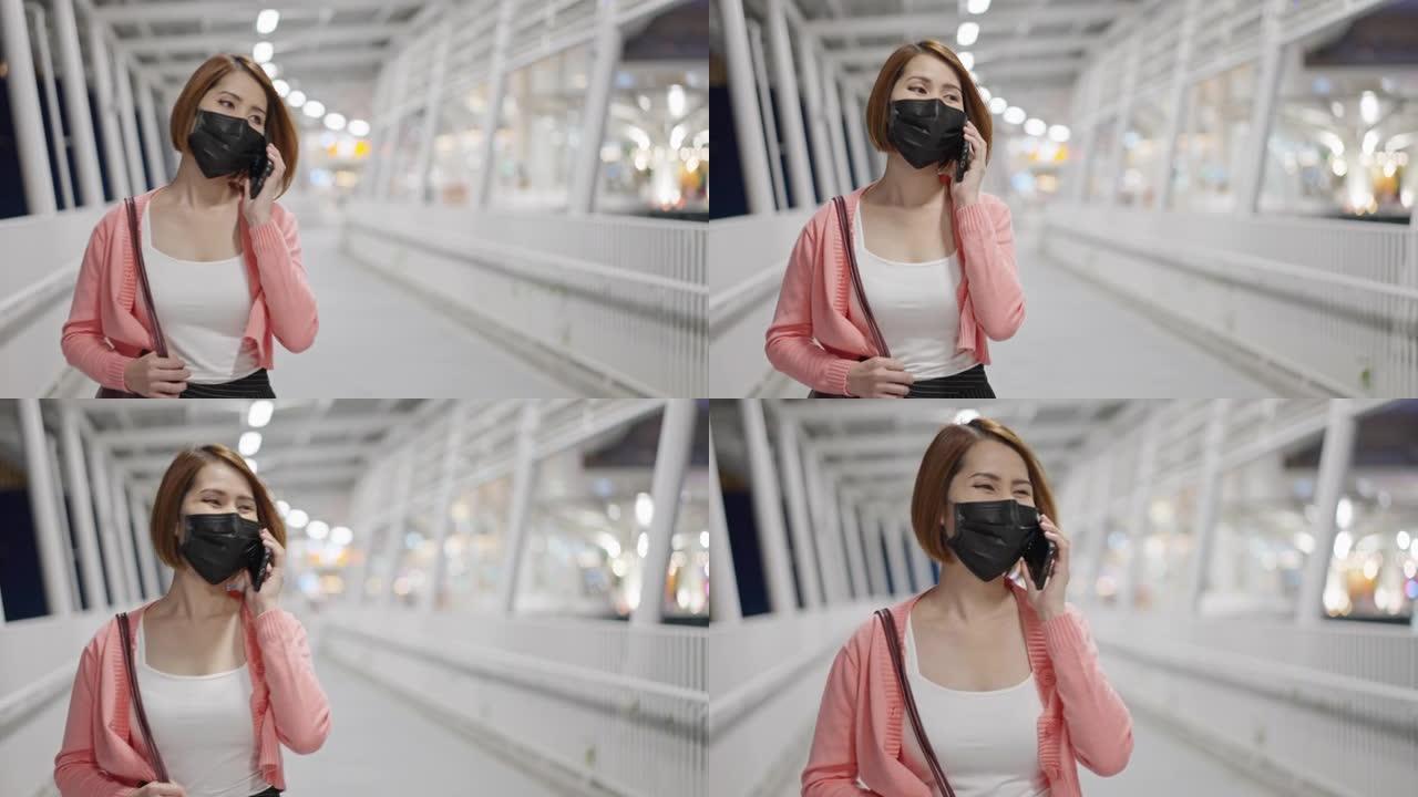 美丽的亚洲女人戴着防护口罩走路和使用智能手机，新常态概念，人们新型冠状病毒肺炎后的生活方式
