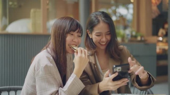 亚洲女性在咖啡馆见面，她的朋友在电话上拍照。