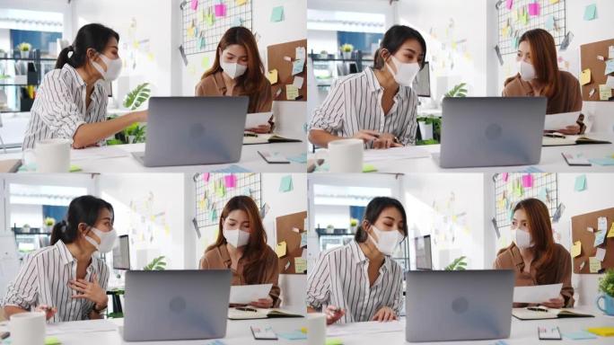 亚洲商人使用计算机演示会议集思广益有关新项目同事的想法，并在新的正常办公室戴防护口罩。