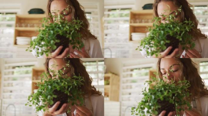 快乐的白人妇女在小屋厨房里闻到植物的味道