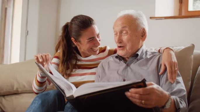 一位怀旧女子的肖像将家庭相册带给她的高级父亲，以便他们可以一起观看照片。老人与女儿分享有趣的回忆和故