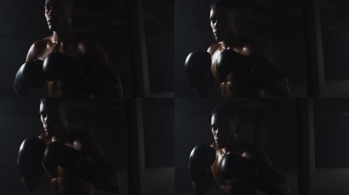 非裔美国男子戴着拳击手套在黑暗的房间里握拳