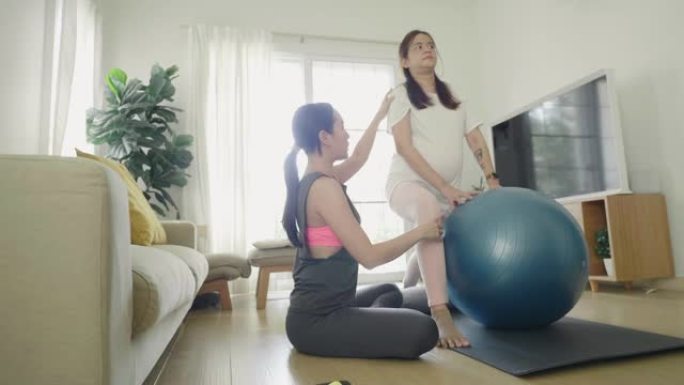 年轻的女瑜伽教练在家为孕妇教授瑜伽。