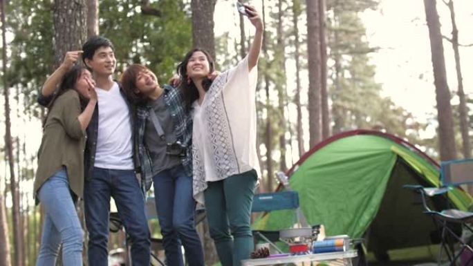 一群朋友四人快乐地走进松树林，在露营区享受