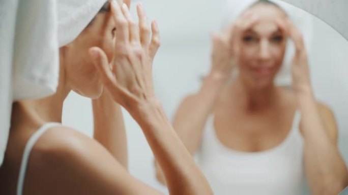 美丽的高加索女人抚摸着她完美柔软的肩膀，脖子，在浴室镜子里看起来很性感。中年女性享受着她的自然美景。
