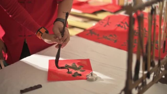 亚洲华裔父亲为农历新年练习中国书法 (吉祥的信息)，并通过在一张红纸上书写女儿来教女儿，握住她的手