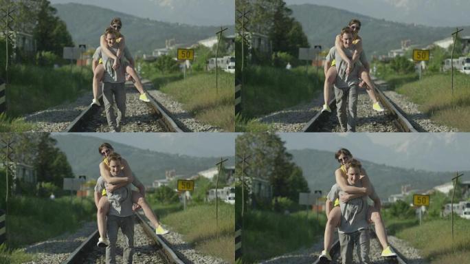 慢动作: 男子在铁轨上背着女友
