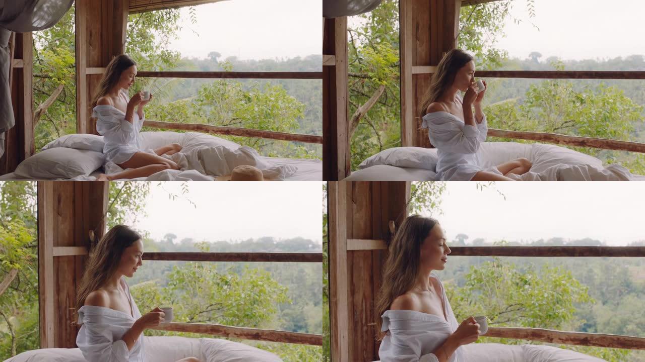 旅行女人在床上喝咖啡在热带酒店度假享受放松的早晨看着丛林的观点