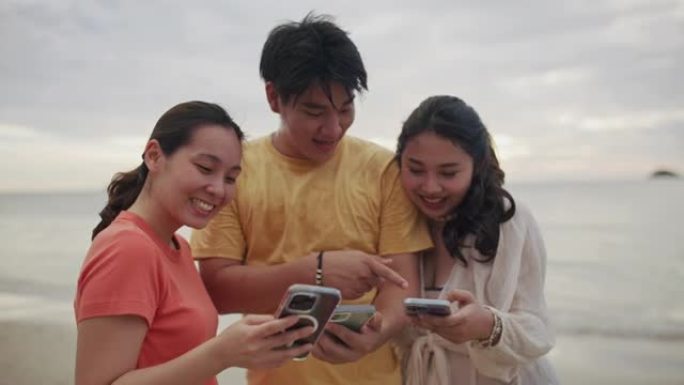 一群朋友使用智能手机的人一起在海滩上享受