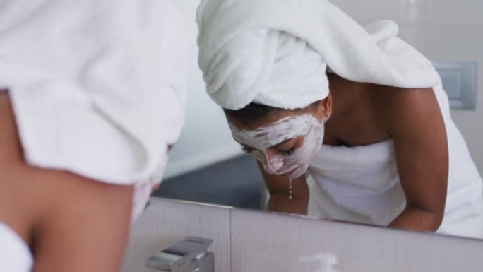 非裔美国妇女在家里的浴室水槽里洗掉口罩