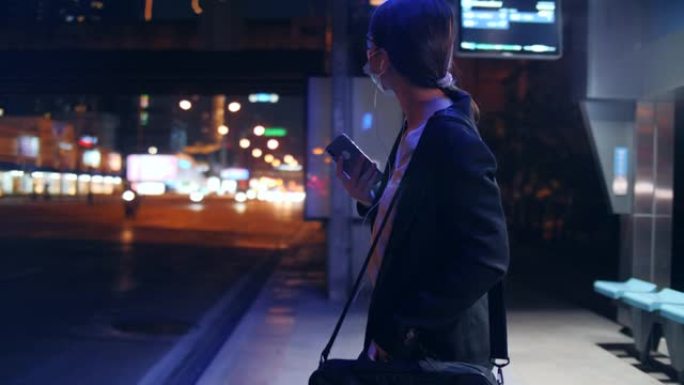 戴着防护面罩的亚洲女商人晚上使用智能手机等公共汽车，在公共交通工具上自我保护