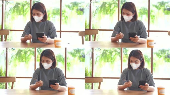 用信用卡支付智能手机的女人在咖啡馆戴着新的普通口罩