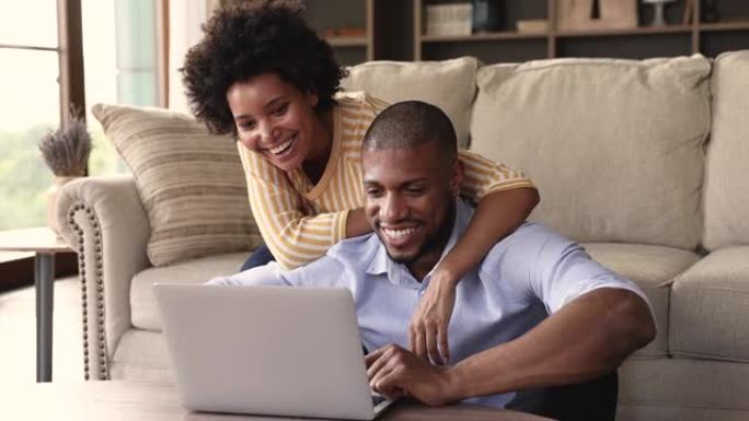 恋爱中的年轻黑人夫妇拥抱在笔记本电脑上观看视频