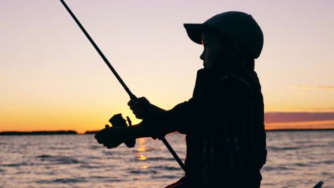 一个孩子在日落时用钓鱼竿钓鱼