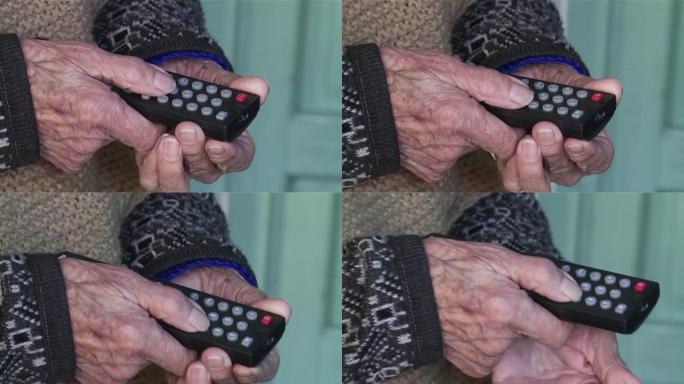 一个拿着电视遥控器的老妇人皱巴巴的手在家里。特写。4k分辨率。