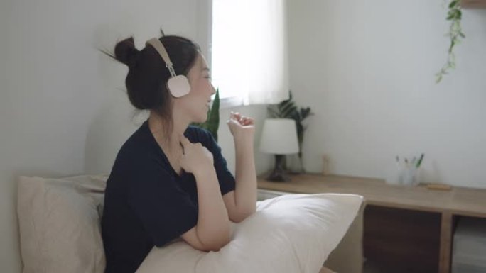 千禧一代亚洲女子戴着耳机在家听音乐不寒而栗