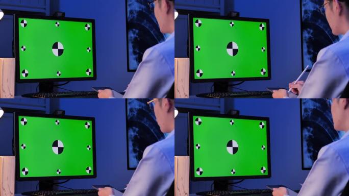 亚洲男医生在晚上工作到很晚的时候在家用电脑远程定位视频会议时看绿屏。家里绿屏