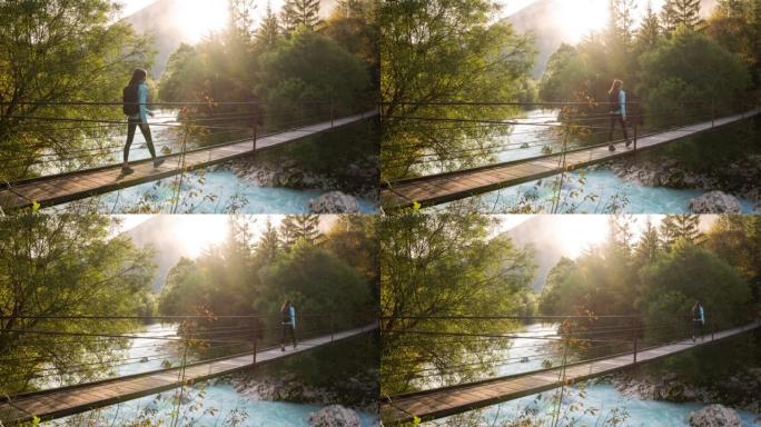 年轻女子早上在山溪上穿木吊桥，风景充满活力