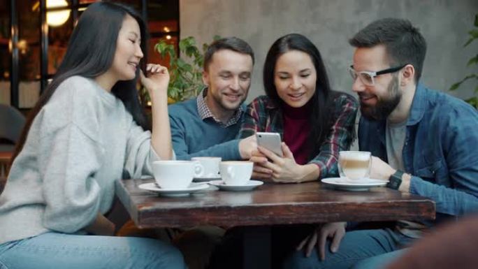 Milti-在舒适的咖啡馆里使用智能手机聊天和大笑的朋友群体