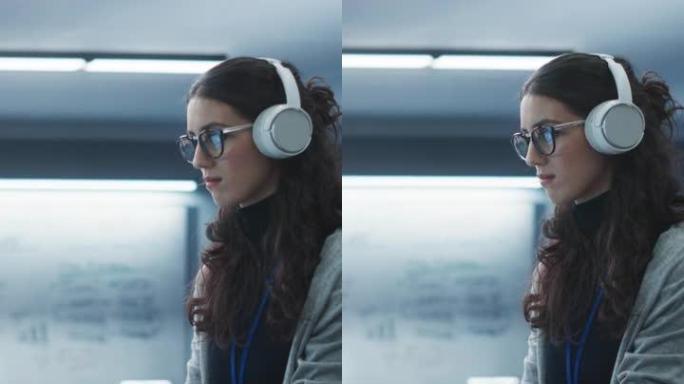 垂直屏幕: 在技术办公环境中工作的年轻工程师的肖像。美丽的多民族女人戴着耳机，为一个区块链项目编写软