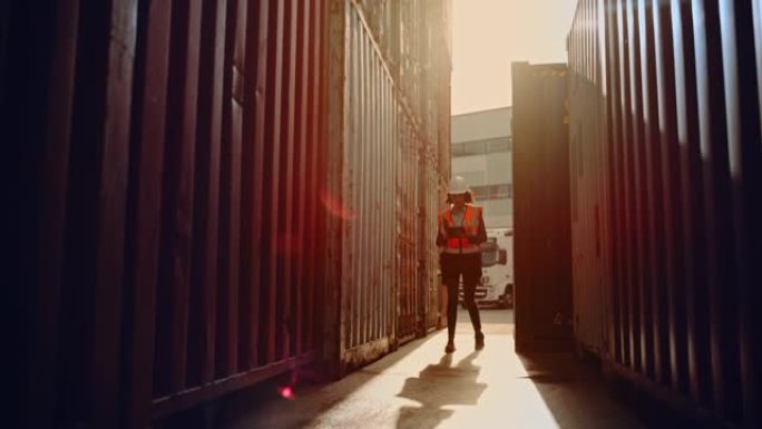 穿着白色安全帽和高能见度背心的拉丁女工业检查员或主管正在物流运输码头仓库用平板电脑检查集装箱。