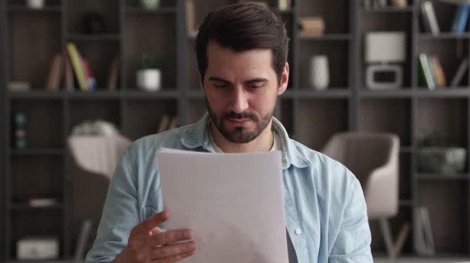 英俊的白人年轻人正在阅读纸质信件。