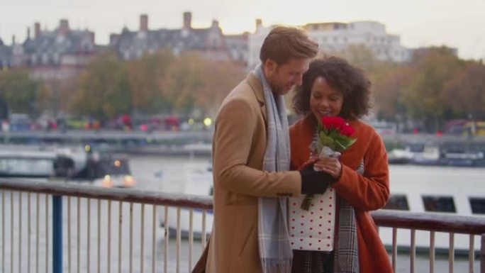 秋天或秋天的夫妇在伦敦泰晤士河上约会，男人给女人礼物和一束鲜花-慢动作拍摄