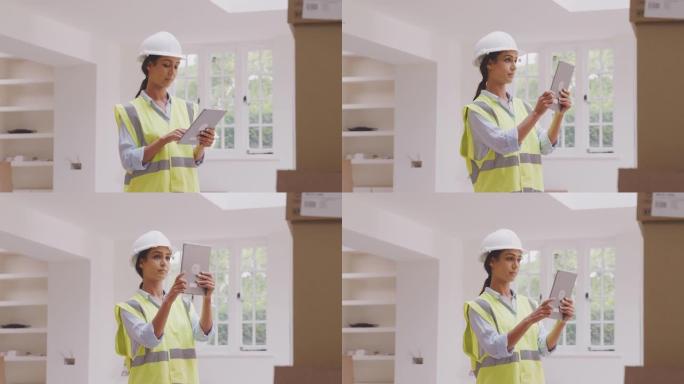 戴着带数字平板电脑的安全帽的女建筑商拍照并检查物业内新厨房单元的交付-慢动作拍摄