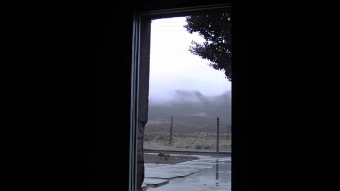 从阿根廷一所乡村学校敞开的大门看，山上有雾多雨的早晨。