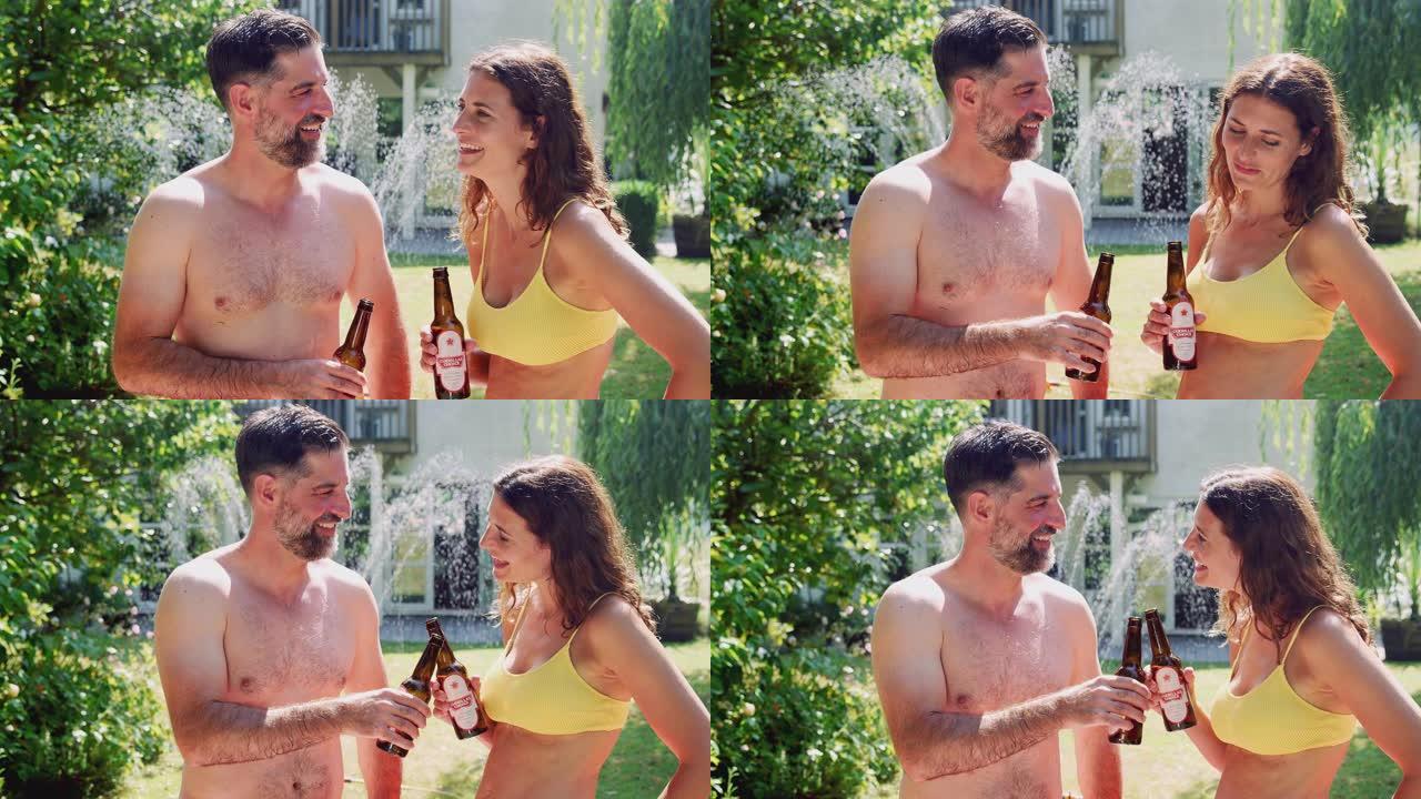 夫妇穿着游泳衣站在夏天的花园里喝啤酒