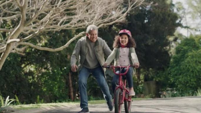 第一次骑自行车，骑自行车和快乐的孩子在户外学习在街上骑自行车。微笑，鼓掌，支持或骄傲的爷爷与孙女度过