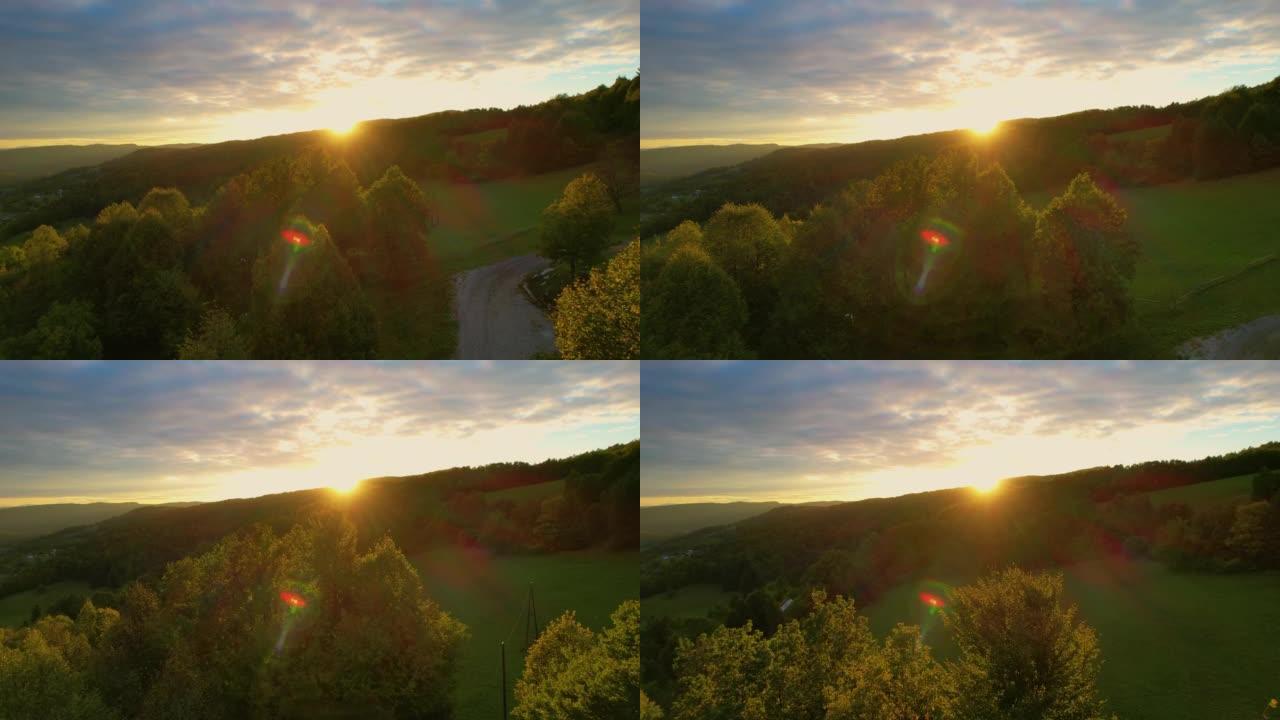 空中: 秋天的太阳落在美丽的丘陵景观后面，森林茂密