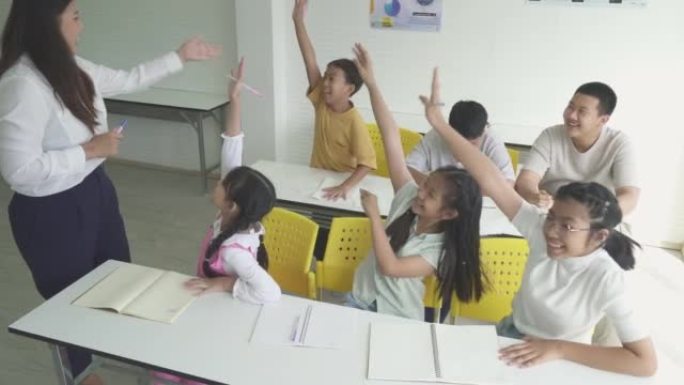 小学生女孩在课堂上举手回答老师的问题。