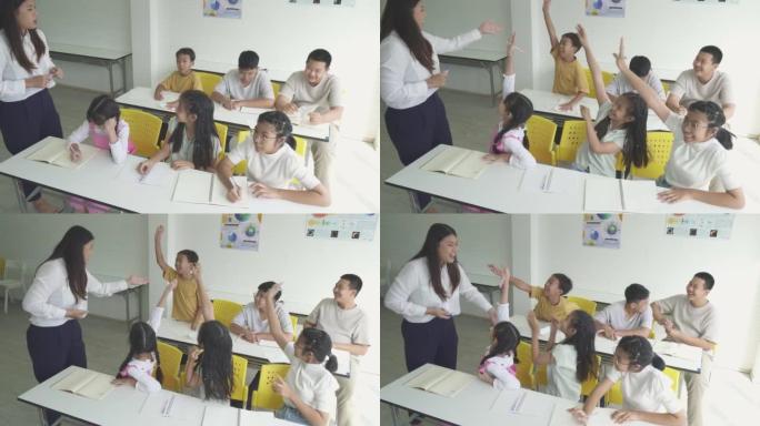 小学生女孩在课堂上举手回答老师的问题。