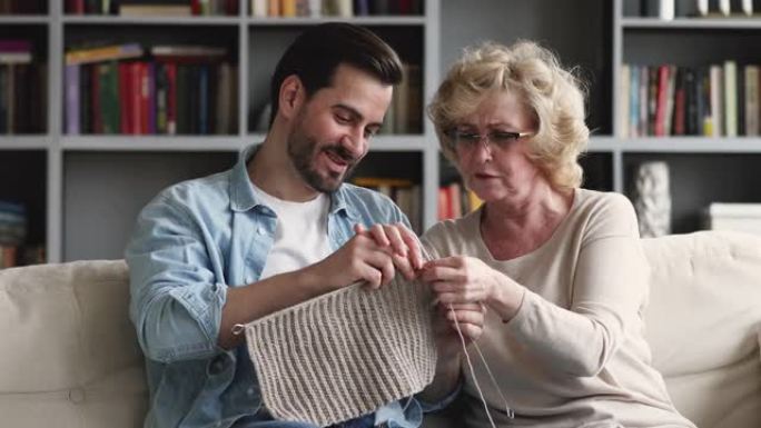 快乐的中年母亲教大人儿子编织保暖衣服。