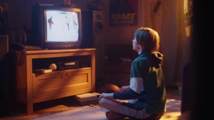 怀旧复古童年概念。小男孩在房间里用过时的内饰在电视上观看曲棍球比赛。支持他最喜欢的球队，当球员进球时
