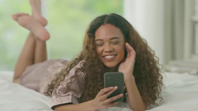 一名年轻女子在家中床上使用智能手机的4k视频片段