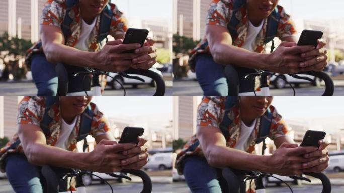 城市中的非裔美国人，使用智能手机坐在街上的自行车上