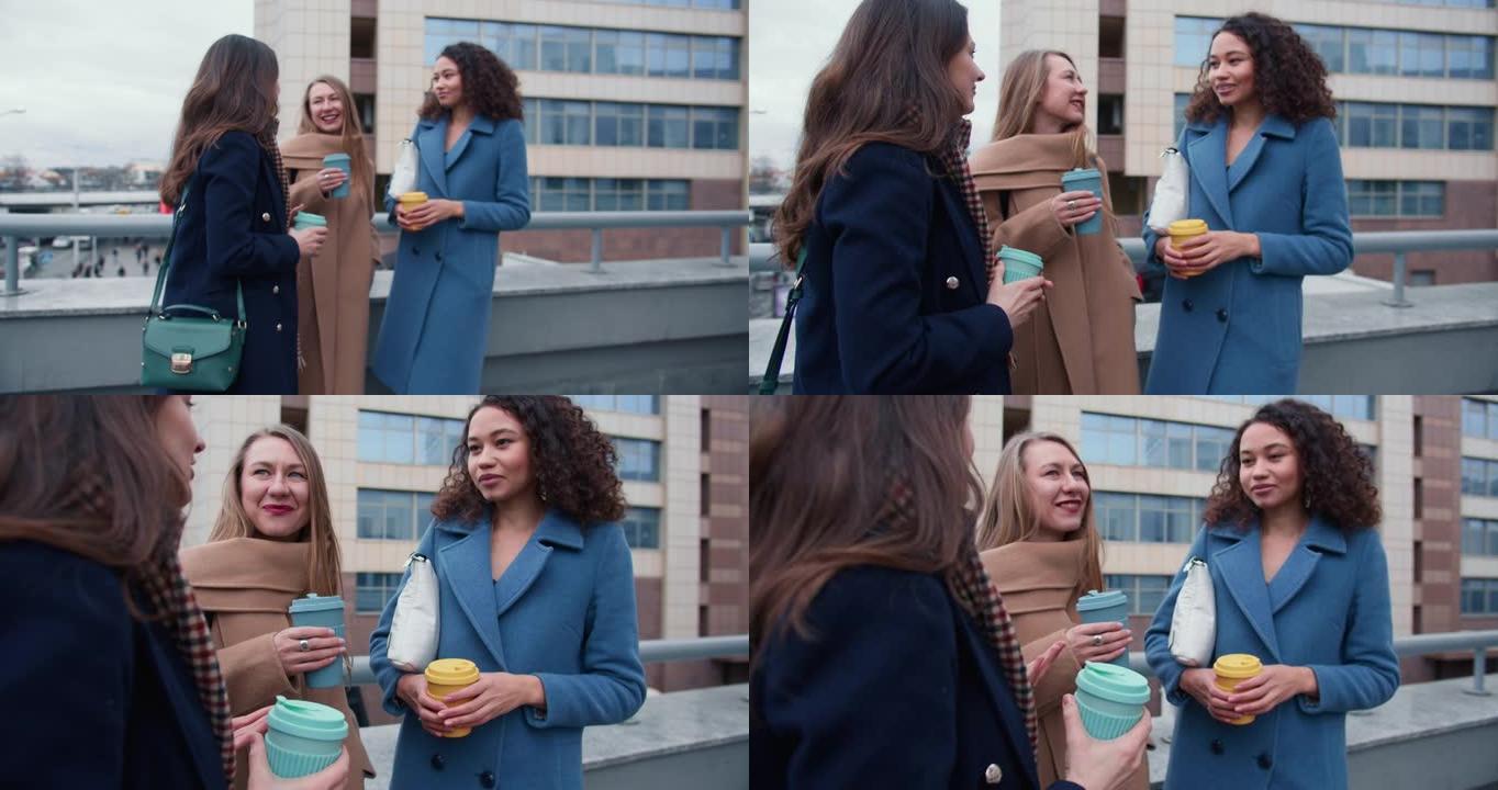 团结概念。在阴天，美丽的多民族年轻女性朋友在外面用生态杯子喝咖啡聊天。