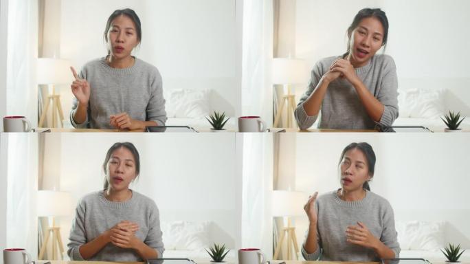 年轻的亚洲女商人在卧室在家工作时，使用电脑笔记本电脑与同事讨论视频通话会议的计划。