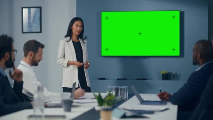办公室会议室会议演示: 积极进取的女性数字企业家演讲，使用绿屏色度键墙电视。成功向一群投资者展示产品