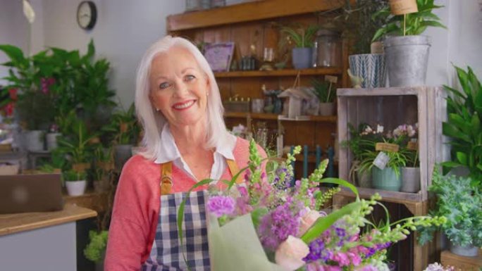 花店商店成熟的女老板拿着一束鲜花的肖像-慢动作拍摄