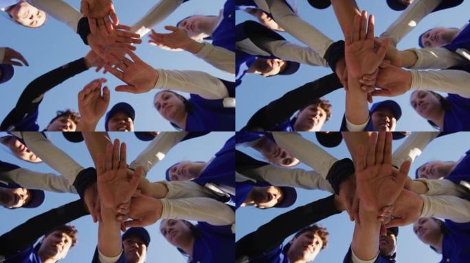 不同群体的女棒球运动员在蓝天下进行手工堆叠的低角度视图