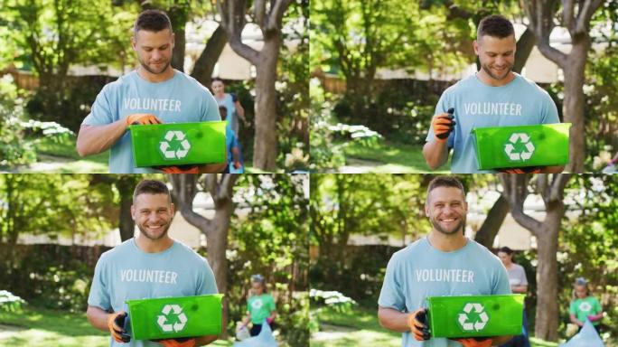 微笑的白人男子穿着志愿者t恤，拿着回收板条箱，收集塑料垃圾