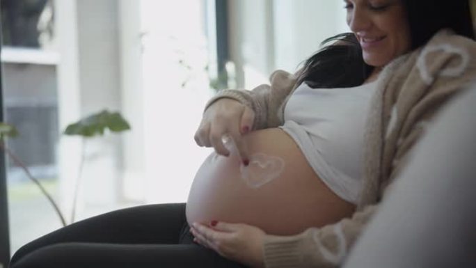 怀孕后期的DS女人用手指在肚子上画一颗心