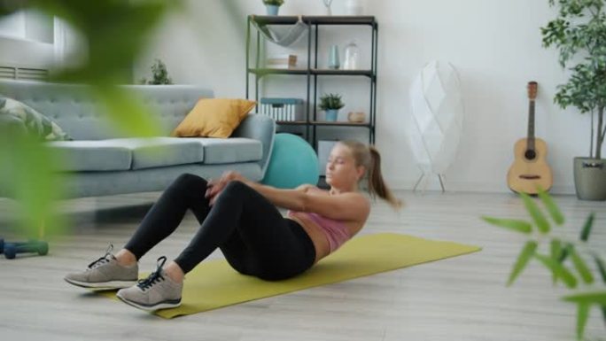 现代公寓瑜伽垫上练习腹肌的女学生慢动作