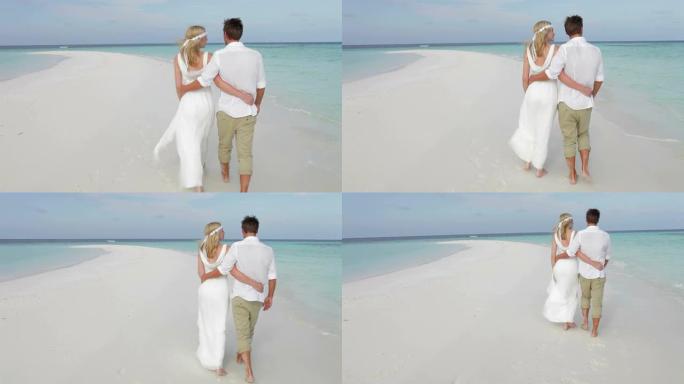 婚礼上沿着海滩散步的夫妇的后视图