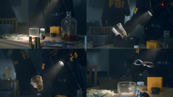 FBI探员在黑暗的公寓里拿着手电筒从厨房桌子上拿杯子
