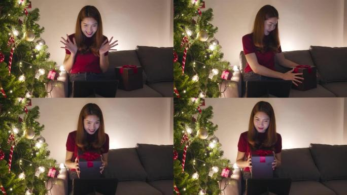 年轻的亚洲女性使用平板电脑视频通话与圣诞礼物盒子的情侣交谈，圣诞树装饰着家里客厅的装饰品。