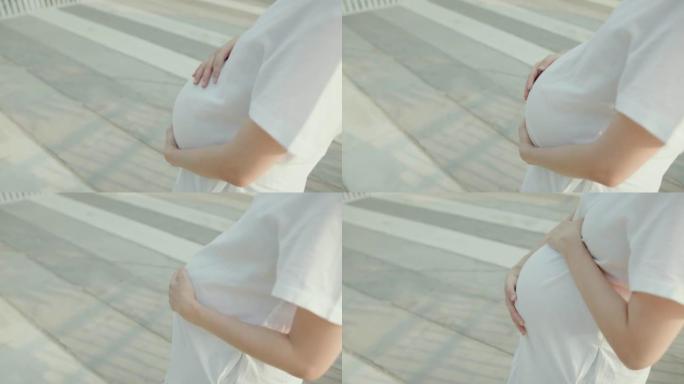 孕妇在公园摸她的大肚子。